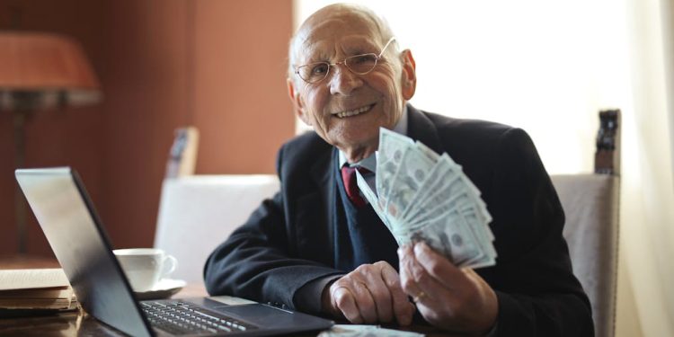 Ilustrasi kekayaan pejabat (dok. Photo by Andrea Piacquadio: https://www.pexels.com/photo/happy-senior-businessman-holding-money-in-hand-while-working-on-laptop-at-table-3823487/)